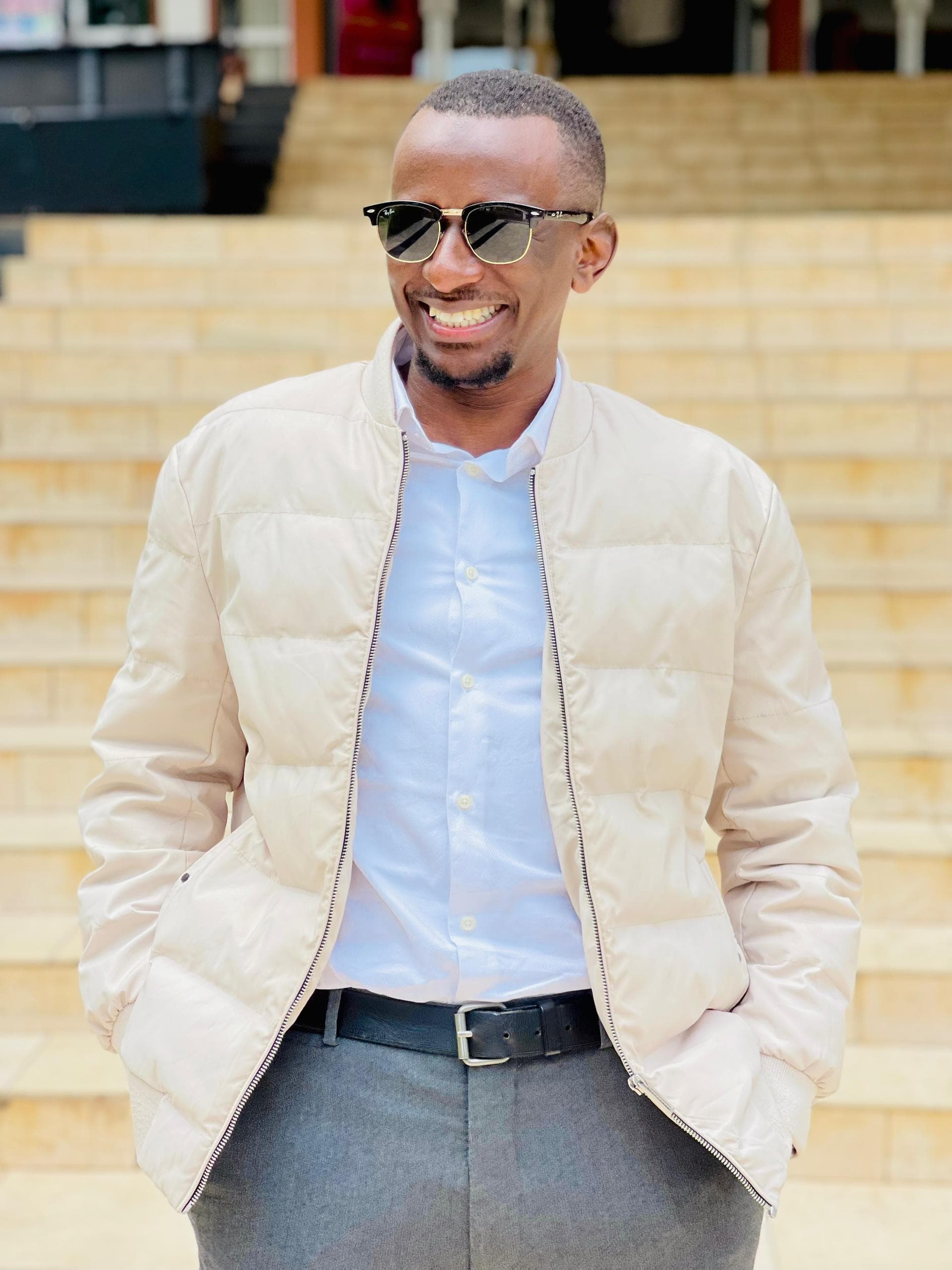 Arafat Magezi smiling, in sunglasses and a cream jacket